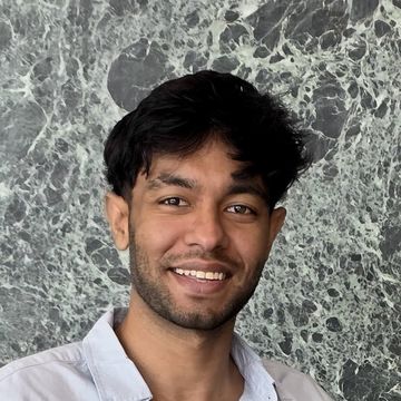 Abrar Khan, smiling, in a light blue shirt against green marble